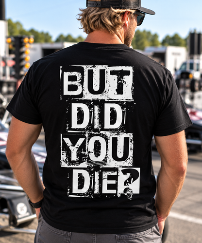 Man wearing black But Did You Die T-shirt with large white distressed back graphic at a drag racing event by Car Chix