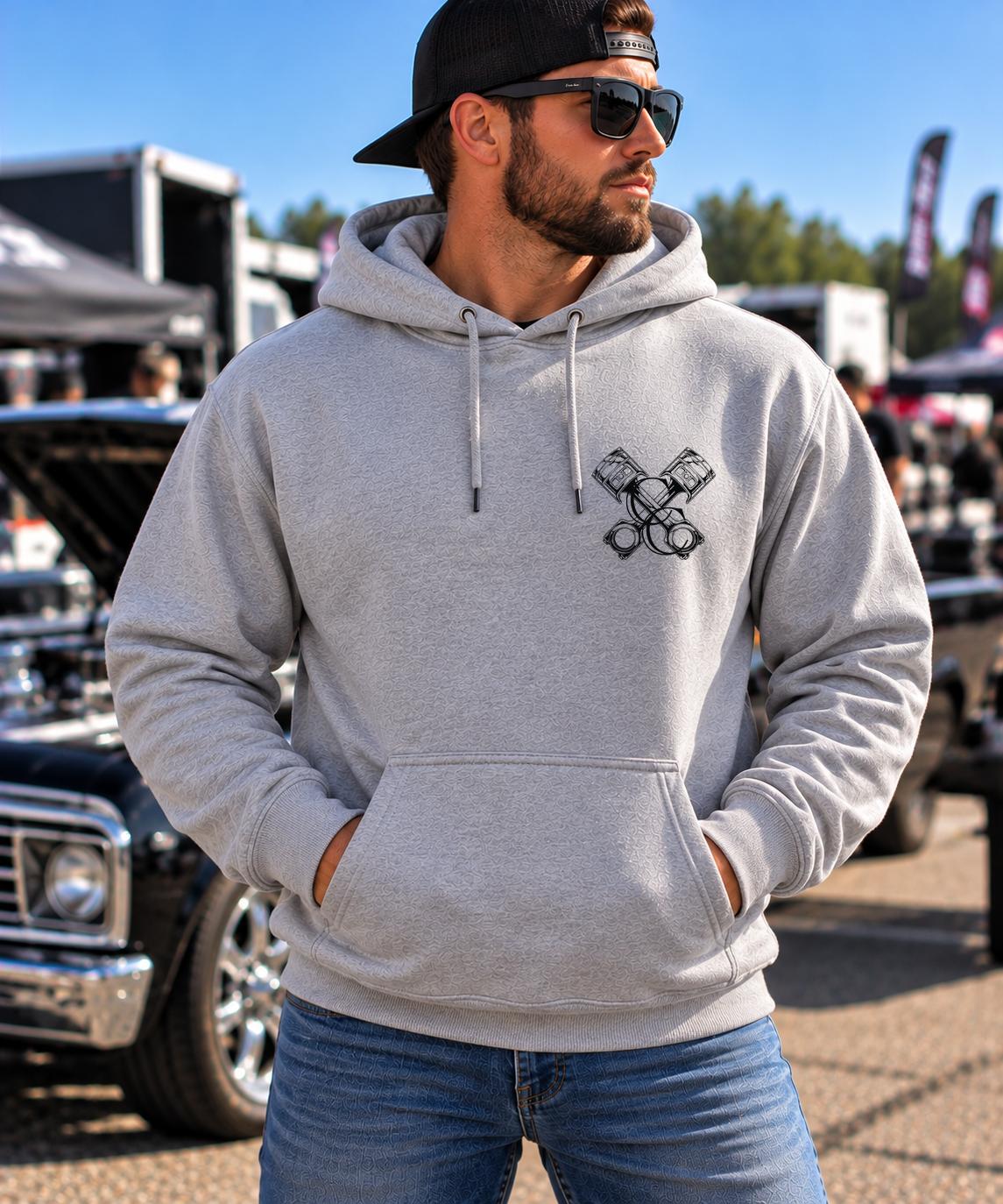 Man modeling grey But Did You Die pullover hoodie, front view at an automotive event, by Car Chix