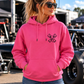 Woman modeling pink But Did You Die pullover hoodie, front view at a drag racing event, by Car Chix