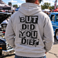 Man wearing grey But Did You Die hoodie with large black distressed back graphic at an outdoor car show by Car Chix