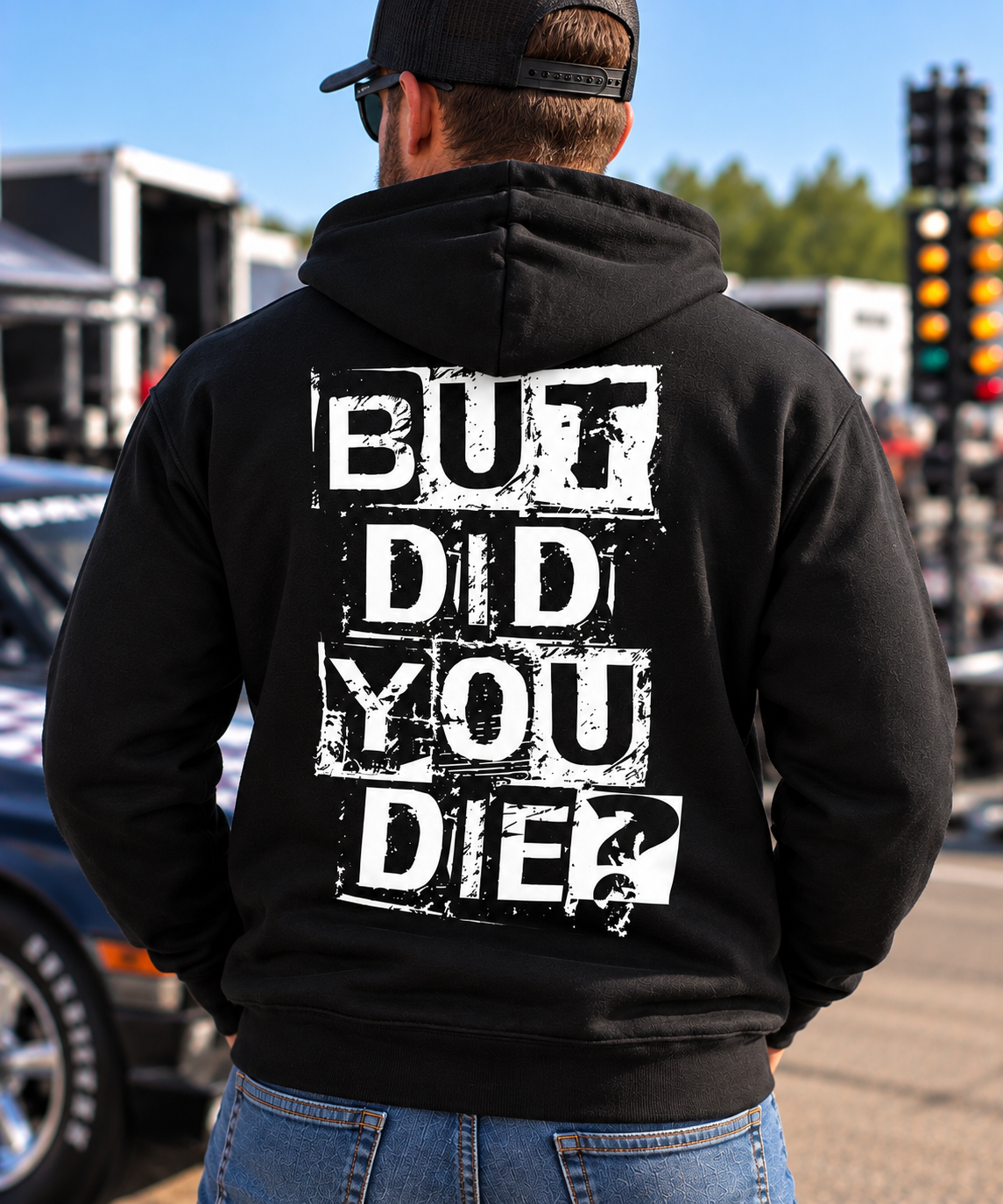 Man wearing black But Did You Die hoodie with large white distressed back graphic at a drag racing event by Car Chix