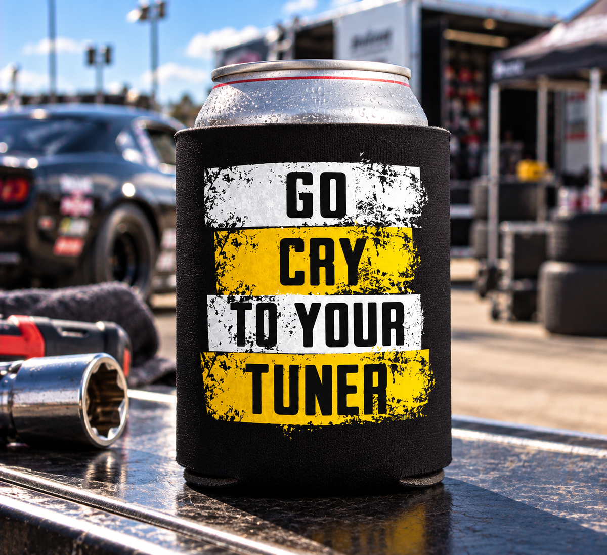Black Car Chix Go Cry to Your Tuner can koozie featuring distressed white and yellow racing graphics with black knockout lettering, displayed at a drag racing event.