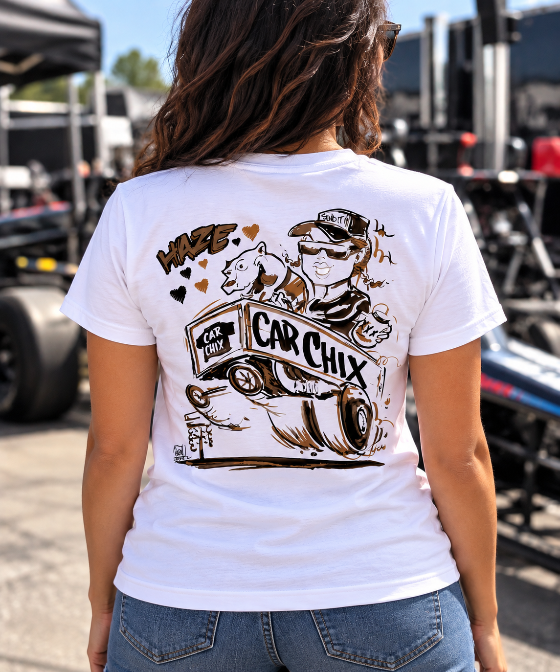 Woman with dark hair wearing white Car Chix Haze Memorial T-shirt featuring Haze tribute artwork on the back at a drag racing event
