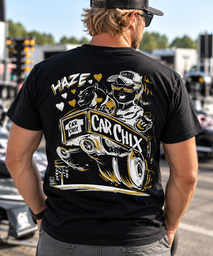 Blonde-haired man wearing black Car Chix Haze Memorial T-shirt featuring Haze tribute artwork on the back at a drag racing event