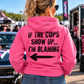 Woman wearing pink Car Chix If The Cops Show Up I'm Blaming hoodie with black distressed lettering and left-pointing arrow on the back at a racing event.