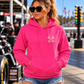 Front view of woman wearing pink Want Me to Go Faster racing hoodie with Car Chix left chest logo