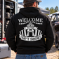 Man wearing black Car Chix Welcome to the Sh*tshow hoodie with large white circus graphic on the back at a motorsports event.