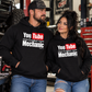 Man and woman wearing black YouTube Certified Mechanic hoodies together in an automotive garage by Car Chix