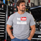 Man wearing light Sport Gray YouTube Certified Mechanic T-shirt with front graphic in an automotive garage by Car Chix