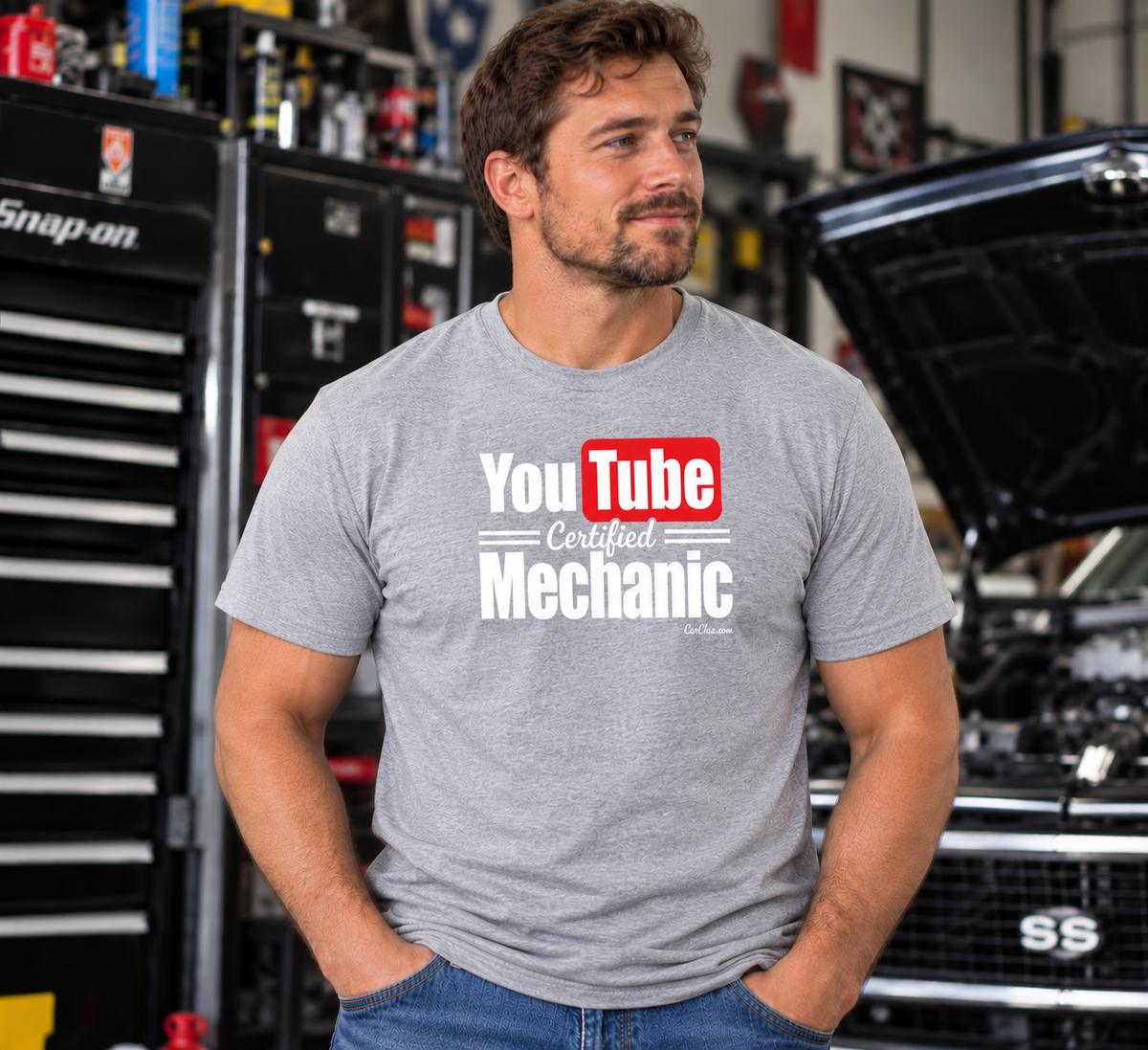 Man wearing light Sport Gray YouTube Certified Mechanic T-shirt with front graphic in an automotive garage by Car Chix