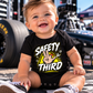 Baby boy wearing black Safety Third racing bodysuit at the racetrack by Car Chix
