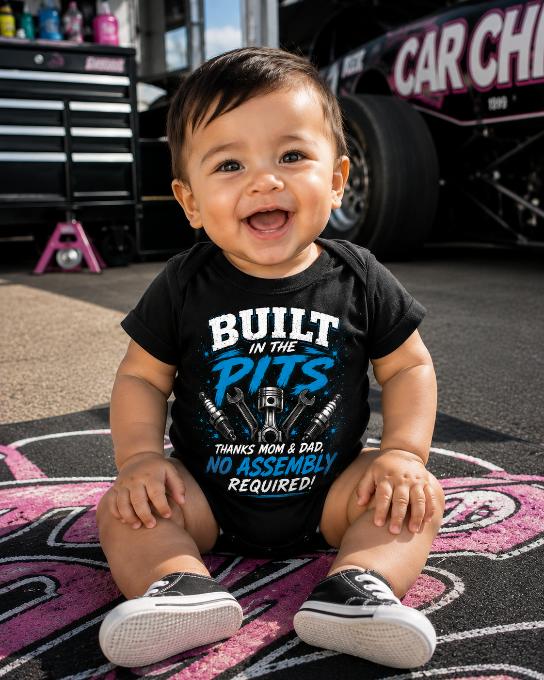Baby boy wearing Built in the Pits Thanks Mom and Dad racing onesie in a race shop
