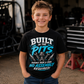 Boy wearing Built in the Pits Thanks Mom and Dad youth racing T-shirt in a race shop