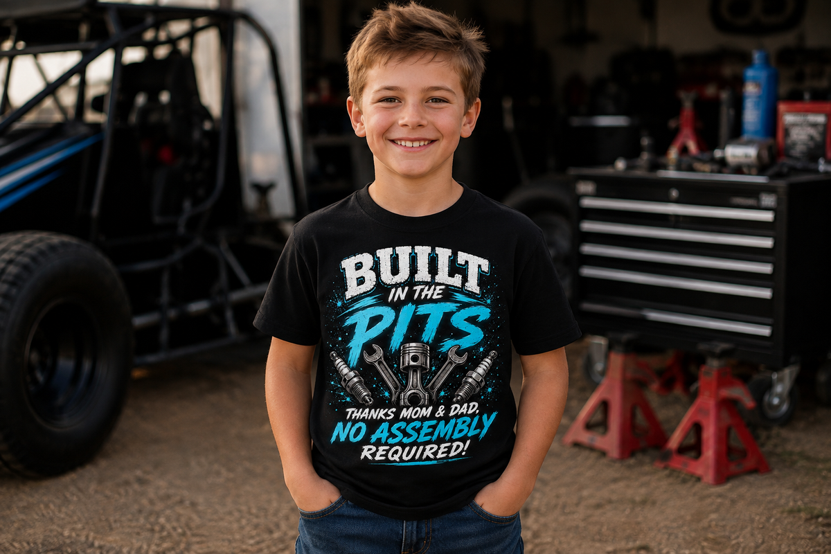Boy wearing Built in the Pits Thanks Mom and Dad youth racing T-shirt in a race shop