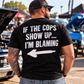 Man wearing black Car Chix If The Cops Show Up I'm Blaming T-shirt with white lettering and pointing arrow on the back at a car show.