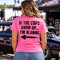 Woman wearing pink Car Chix If The Cops Show Up I'm Blaming T-shirt with distressed black lettering and left-pointing arrow on the back at a motorsports event.