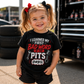 Toddler girl wearing I Learned My First Bad Word in the Pits kids racing tee in the pits
