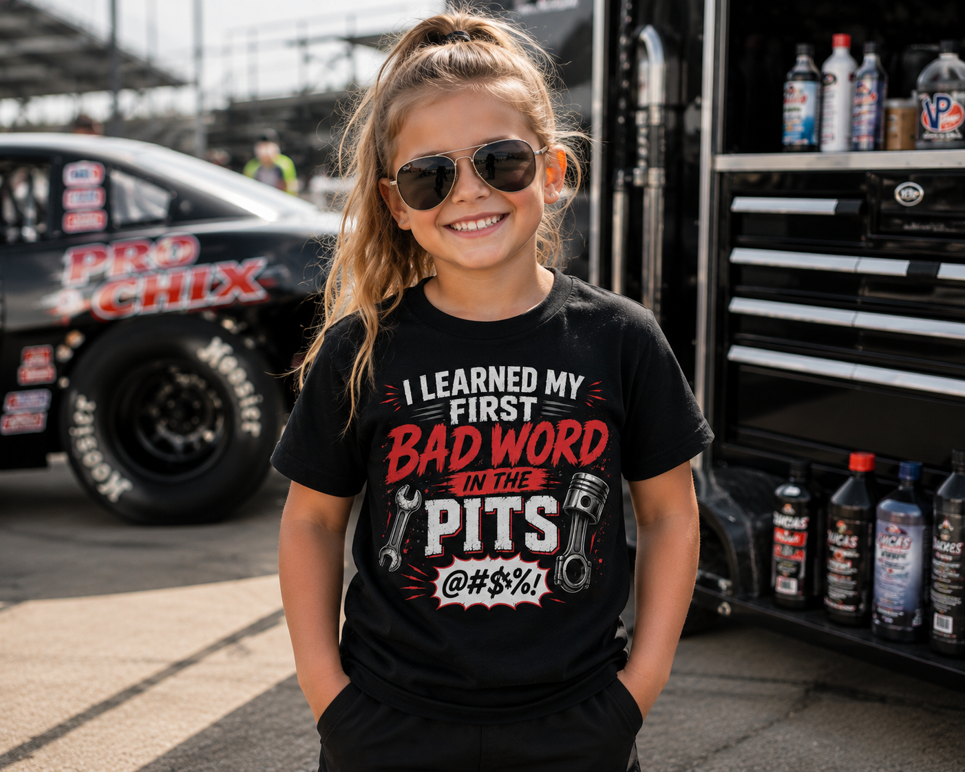 Girl wearing I Learned My First Bad Word in the Pits kids racing tee in the pits