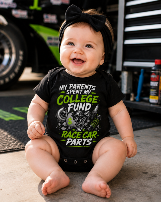 Baby wearing College Fund Race Car Parts infant racing bodysuit in a motorsports garage