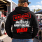 Man wearing black Car Chix Unless It's About Racing IDGAF hoodie featuring large red and white warning graphic on the back at a motorsports racing event.
