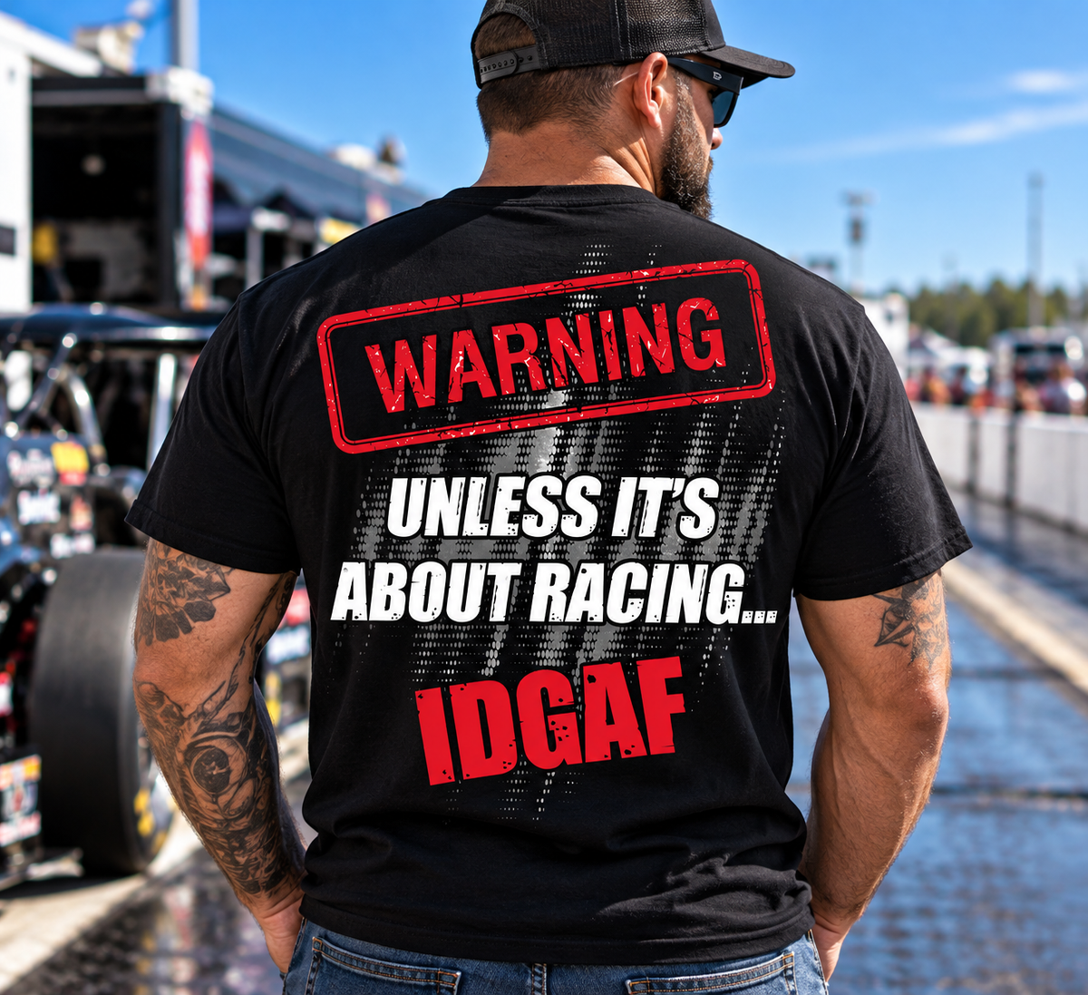 Man wearing black Car Chix Unless It's About Racing IDGAF T-shirt featuring large red and white warning graphic on the back at a drag racing event.