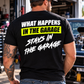 Man wearing a black Car Chix What Happens in the Garage Stays in the Garage T-shirt with white lettering and neon yellow graphic, standing in an automotive garage.